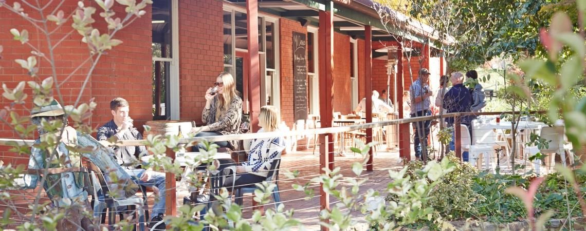 Groups of friends enjoying relaxed drinks  in a country beer garden under decking